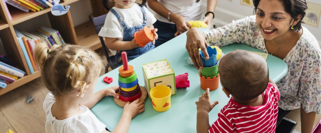 Nursery children playing with teacher in the classroom